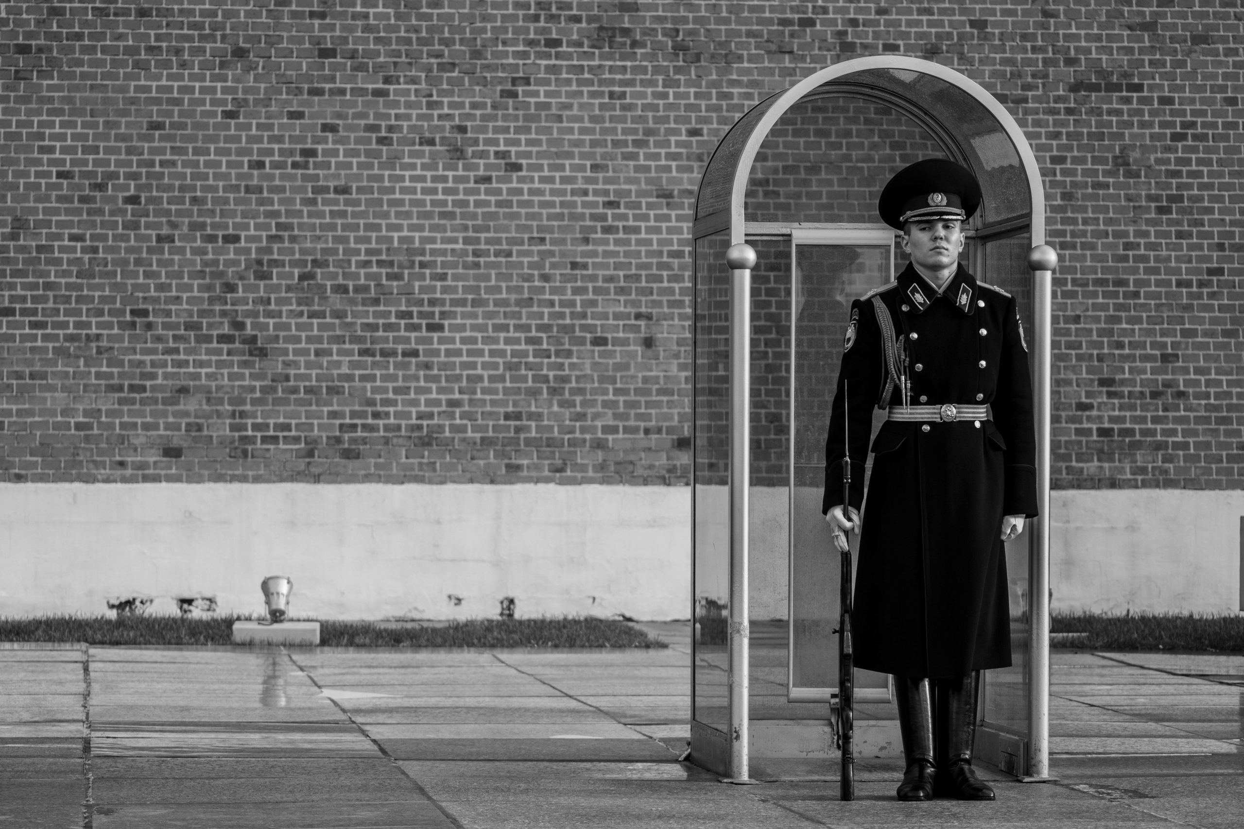 A uniformed guard stands vigilantly at an outdoor duty post, exemplifying dedication and service.